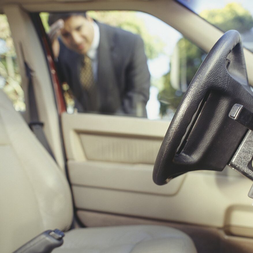 Businessman looking through window at keys locked in car Businessman looking through window at keys locked in car