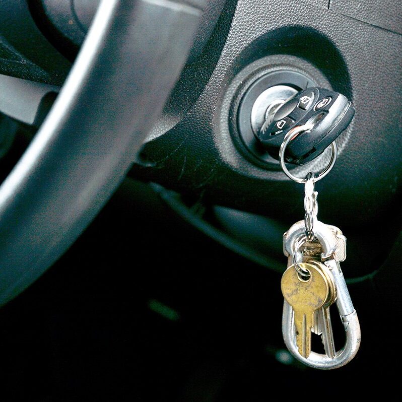 Car keys in the ignition Shot of Car key and house key dangling from the ignition of car
