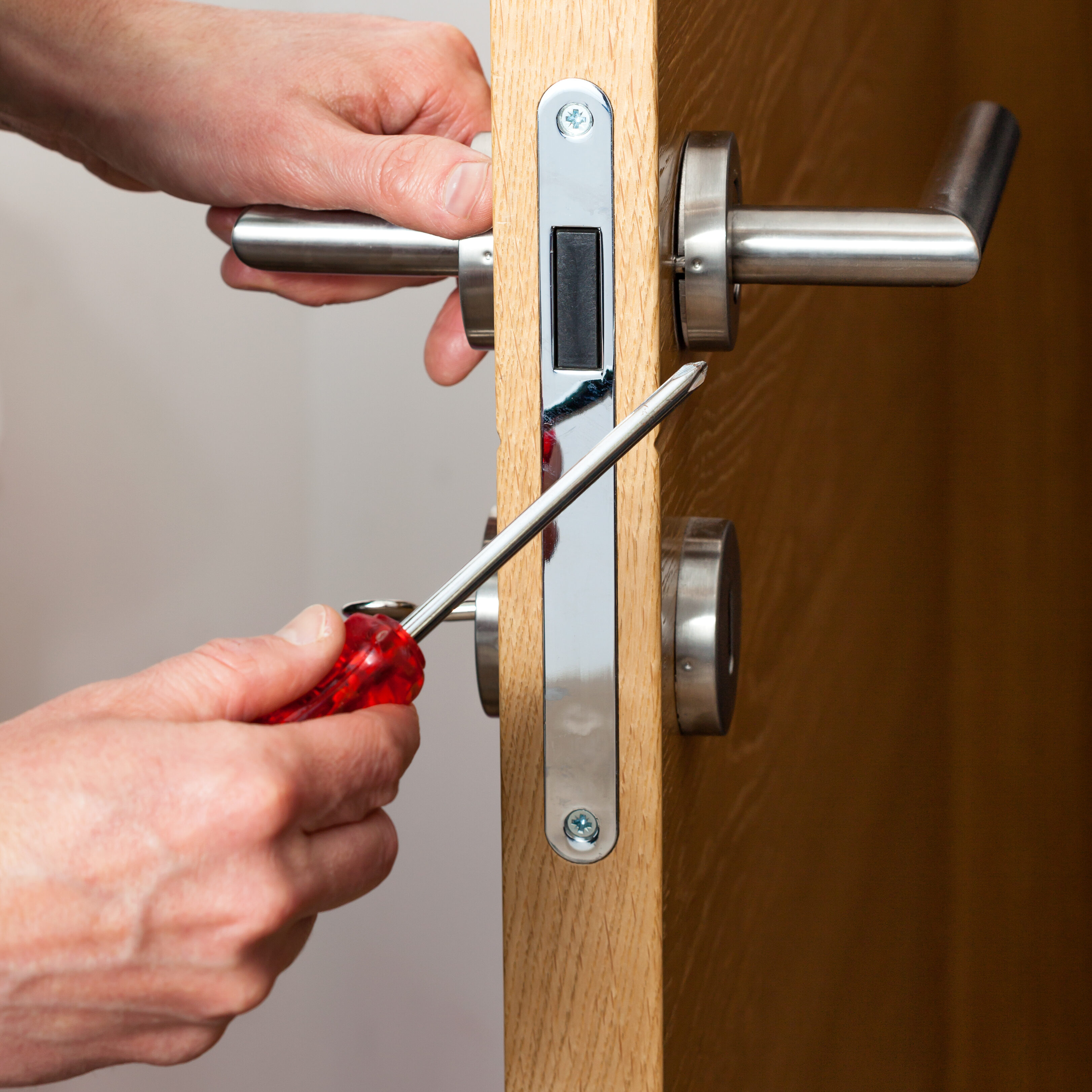 Hands repairing a door lock Hands repairing a door lock with a screwdriver